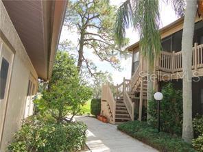 A walkway leads between two multi-story residential buildings with wooden stairs and screened balconies — 5753 AVISTA DRIVE, SARASOTA, FL