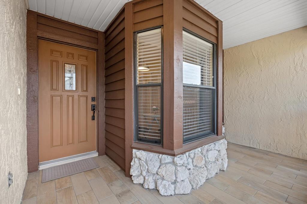 A front entryway features a brown door, a bay window with stone siding, and tiled flooring — 5753 AVISTA DRIVE, SARASOTA, FL