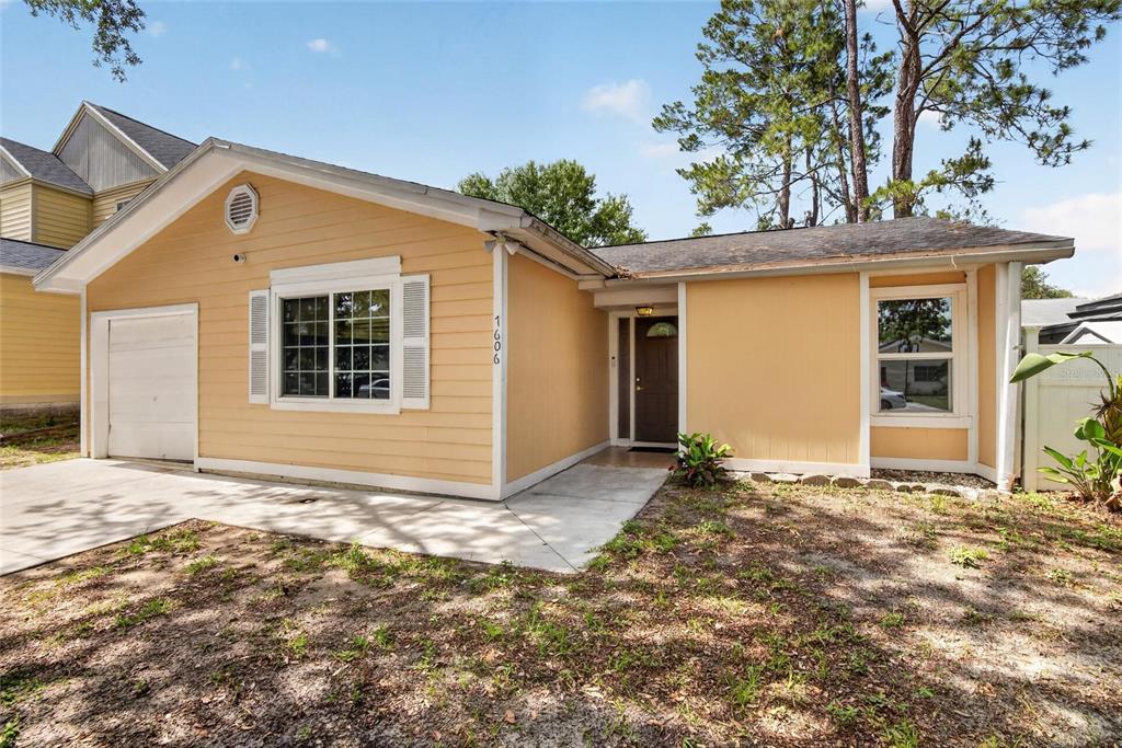 A single-story yellow house with a garage, a front entrance, and a concrete driveway — 7606 LEON AVENUE, TAMPA, FL