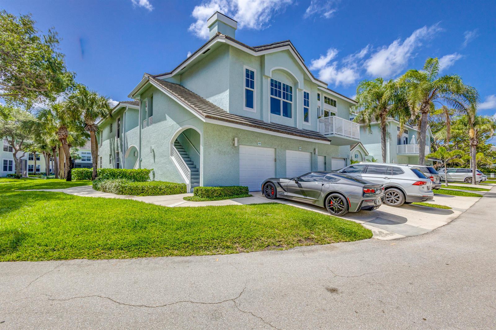 A light green two-story townhouse features a two-car garage, an exterior staircase, and a balcony — 1701 Mizzenmast Way, Jupiter FL 33477, JUPITER, FL