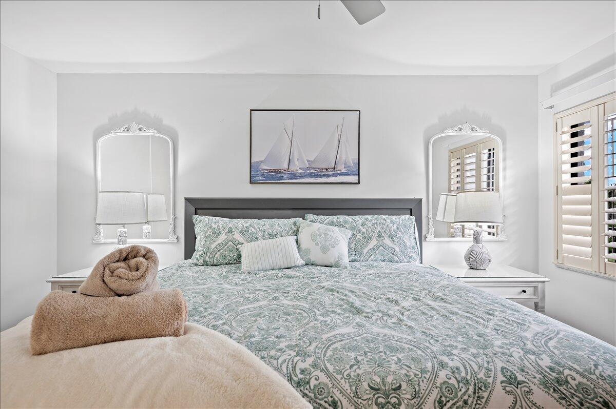 A bedroom features a bed with patterned bedding, two white nightstands, and two wall mirrors — 1605 S Us Highway 1 # A303, Jupiter FL 33477, JUPITER, FL