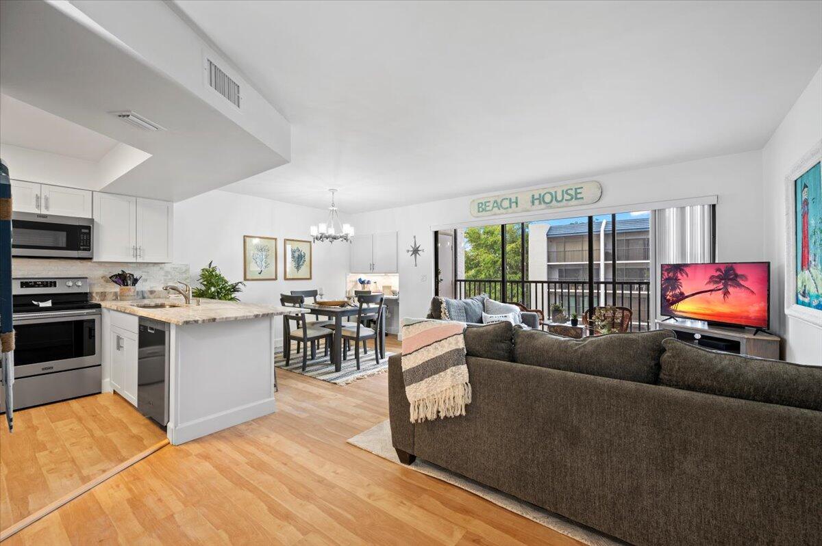 An open-concept living and dining area features a kitchen with white cabinets and wood flooring — 1605 S Us Highway 1 # A303, Jupiter FL 33477, JUPITER, FL