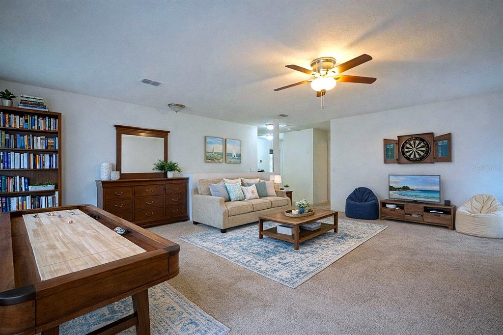 A living room features a shuffleboard table, a sofa, a television, and a ceiling fan — 436 GREAT FALLS LANE SW, PALM BAY, FL