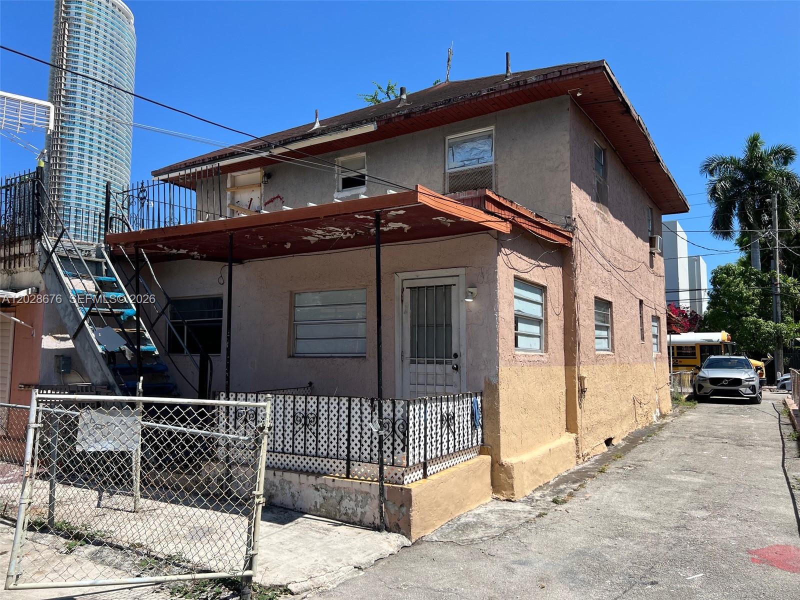 A two-story stucco building with an exterior staircase and a small front porch — MIAMI, FL