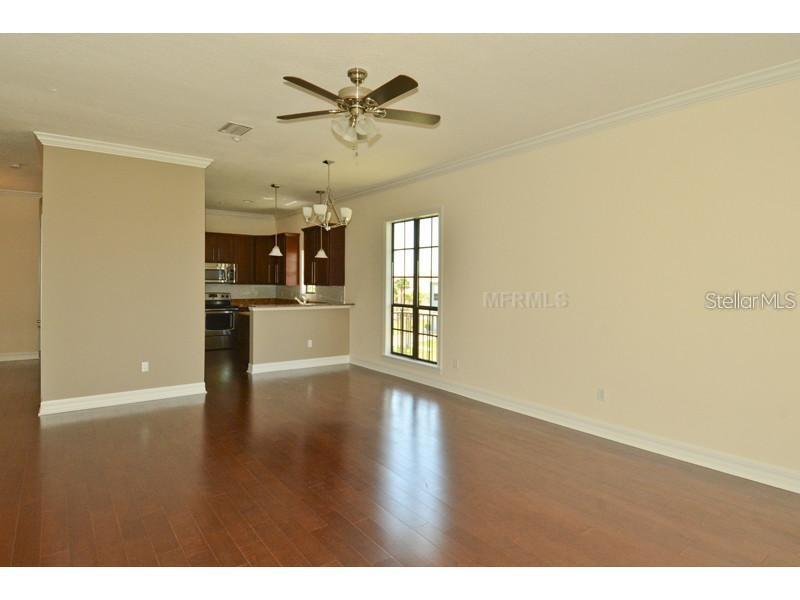 An open-concept living room with hardwood floors, a ceiling fan, and an adjacent kitchen — 6404 MARGARITA SHORES LANE, APOLLO BEACH, FL
