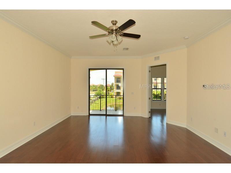 An empty room with hardwood floors, a ceiling fan, and a sliding glass door balcony — 6404 MARGARITA SHORES LANE, APOLLO BEACH, FL