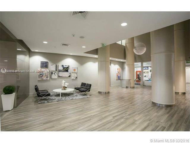 A modern lobby features light wood-look flooring, cylindrical columns, and a small seating area — 1750 N Bayshore Dr # 2806, Miami FL 33132, MIAMI, FL