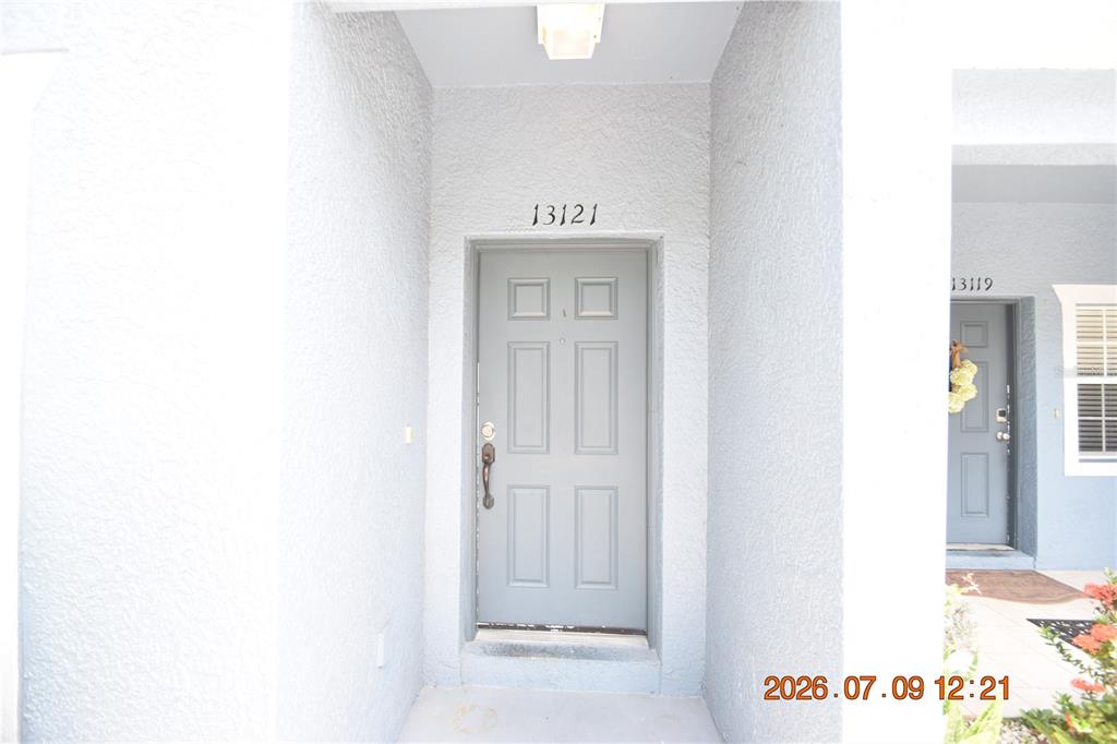 A gray front door with the number 13121 above it is set in a stucco entryway — 13121 KINGS CROSSING DRIVE, GIBSONTON, FL