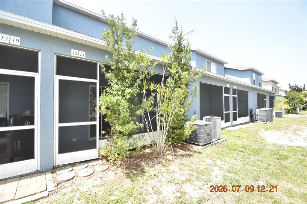 The exterior of a blue multi-unit building features screened-in patios and outdoor air conditioning units — 13121 KINGS CROSSING DRIVE, GIBSONTON, FL