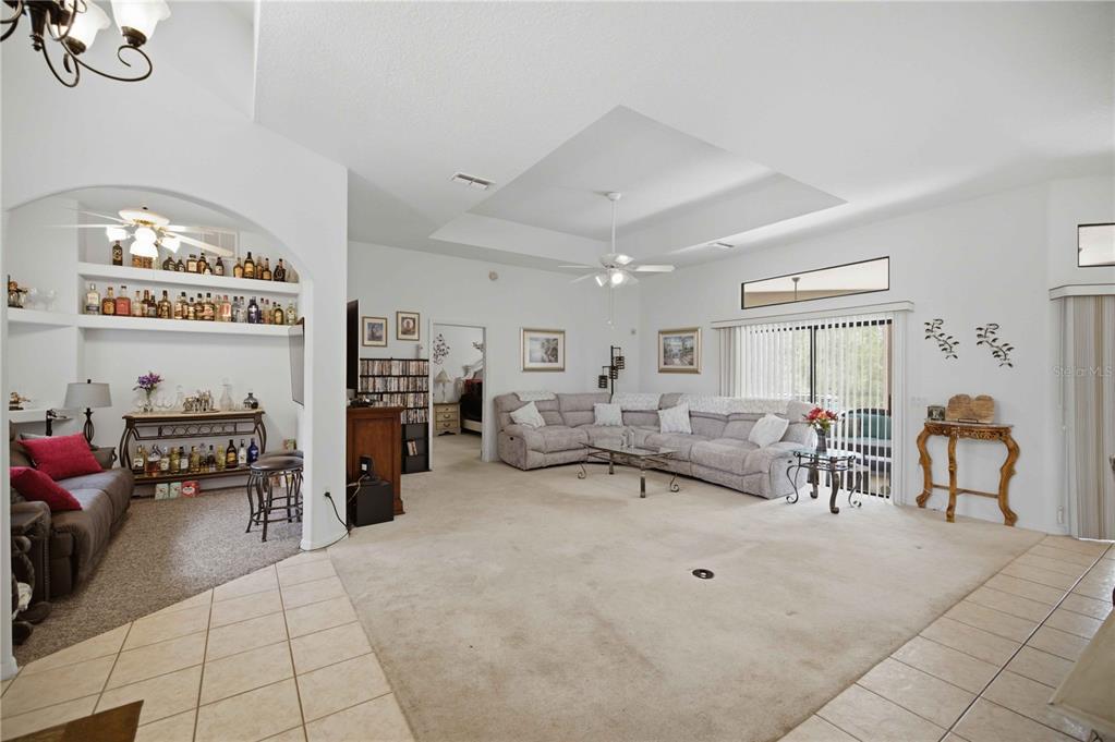 A spacious living room features a tray ceiling, beige carpeting, and an arched bar area — 4710 W MUSTANG BOULEVARD, BEVERLY HILLS, FL