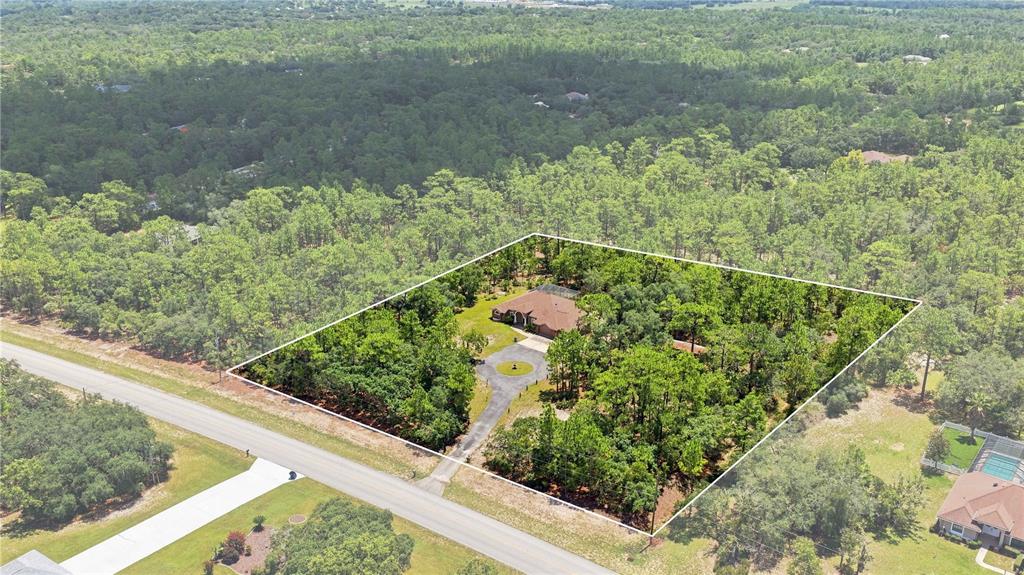 An aerial view shows a house with a circular driveway surrounded by dense trees — 4710 W MUSTANG BOULEVARD, BEVERLY HILLS, FL
