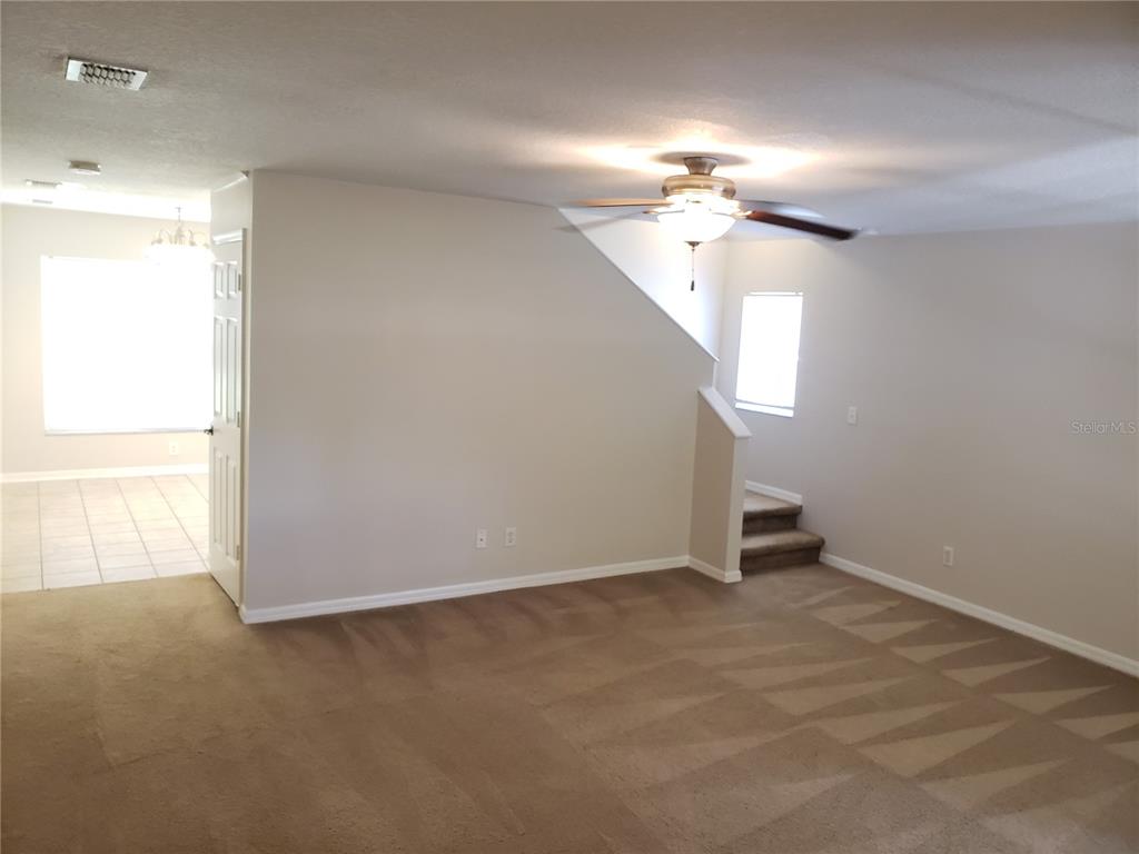 A carpeted living room features a ceiling fan, a staircase, and an adjacent tiled area — 15114 DEER MEADOW DRIVE, LUTZ, FL