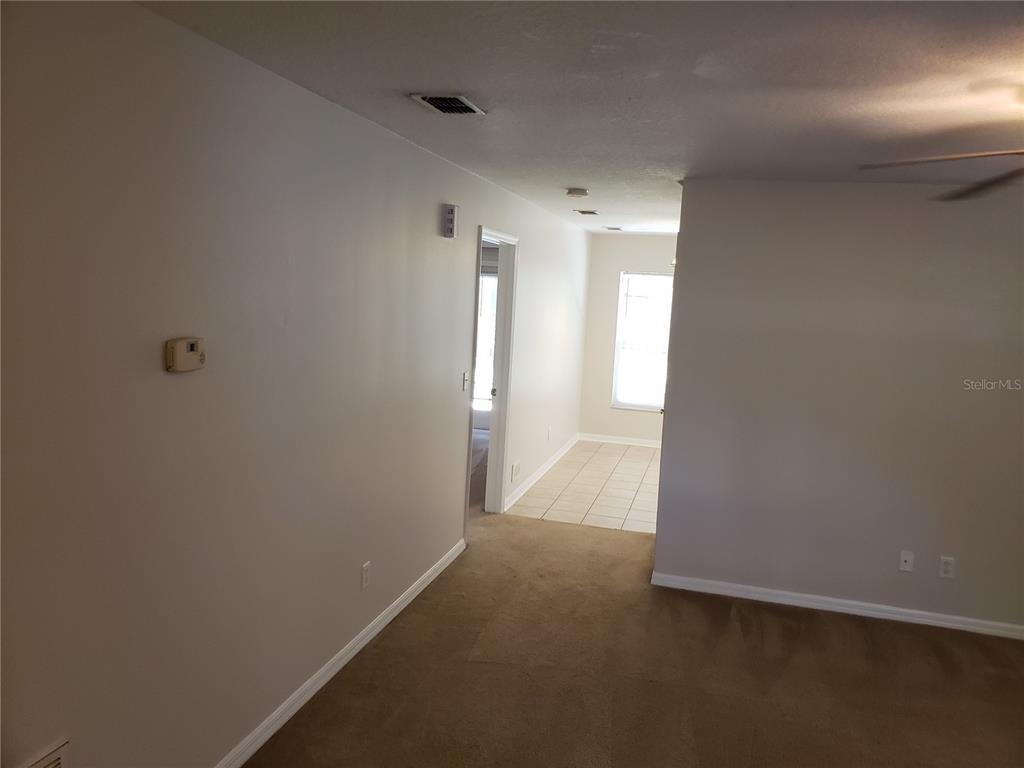 A carpeted living area leads to a tiled hallway and a room with a window — 15114 DEER MEADOW DRIVE, LUTZ, FL