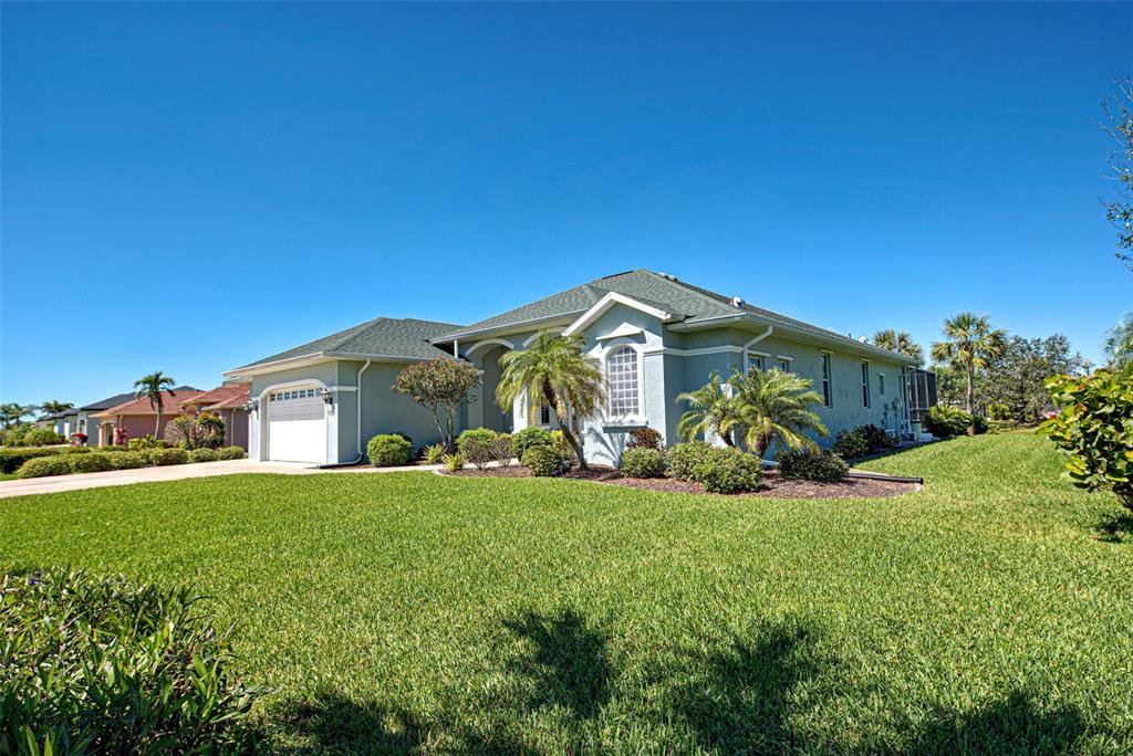 A light-colored single-story house with a garage and palm trees sits on a grassy lawn — 1078 BOUNDARY BOULEVARD, ROTONDA WEST, FL