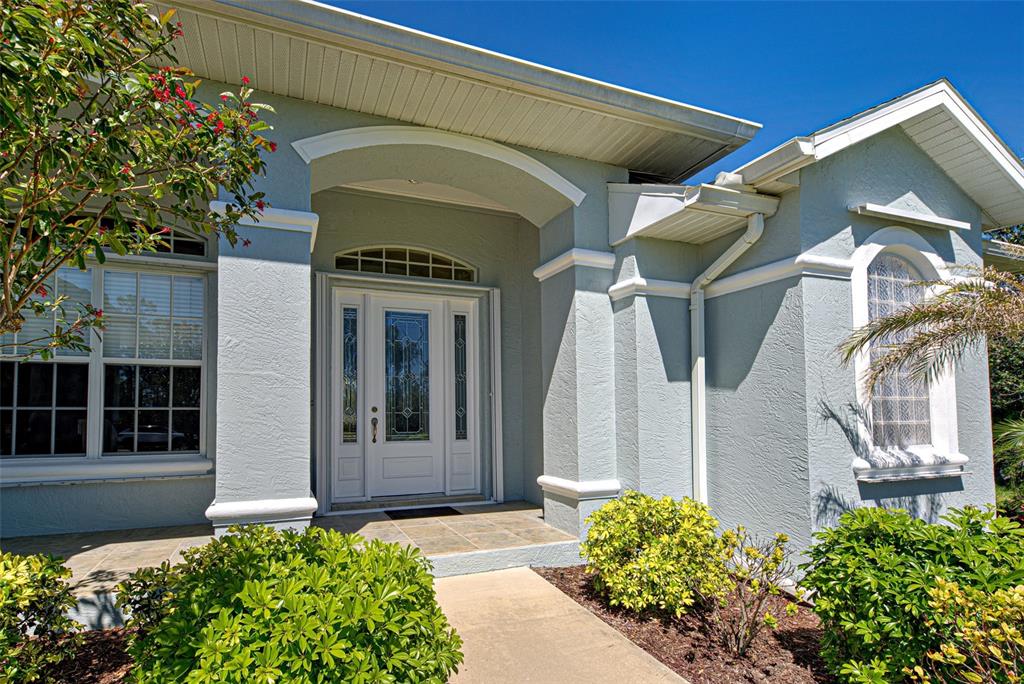 The exterior of a light blue house features a white front door and arched entryway — 1078 BOUNDARY BOULEVARD, ROTONDA WEST, FL