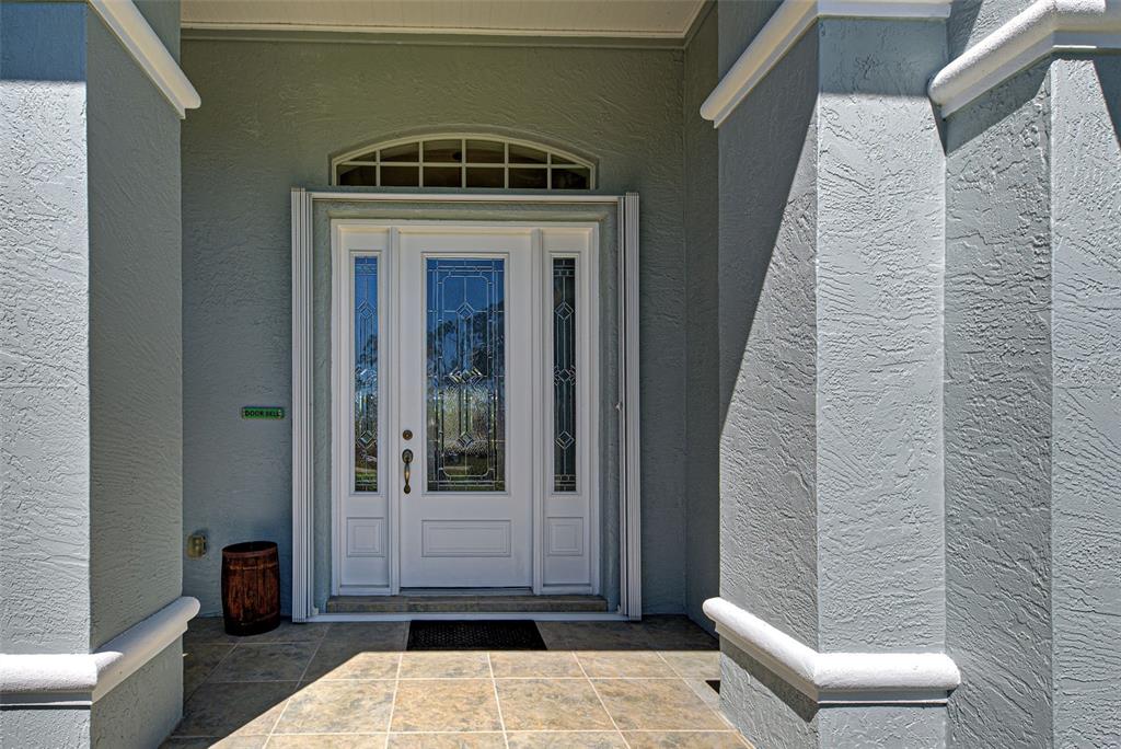 A white front door with glass panels is framed by two gray stucco pillars — 1078 BOUNDARY BOULEVARD, ROTONDA WEST, FL