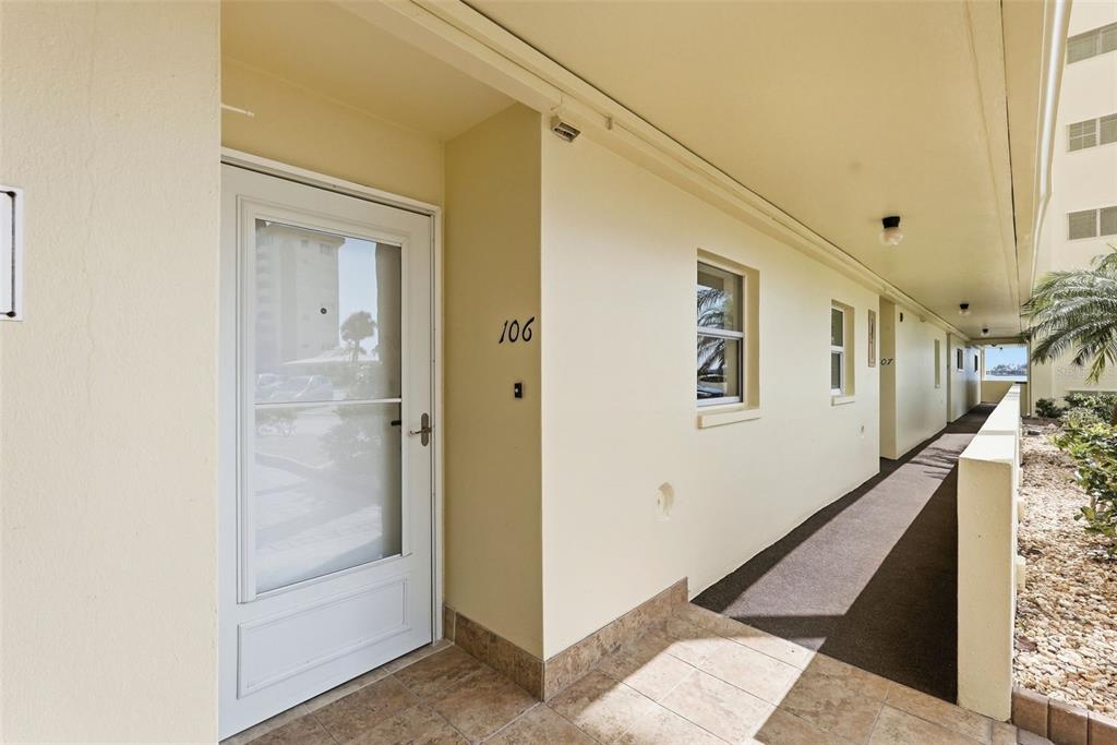 An exterior view of a building hallway featuring unit 106 with a white storm door — 4775 COVE CIRCLE UNIT 106, ST PETERSBURG, FL