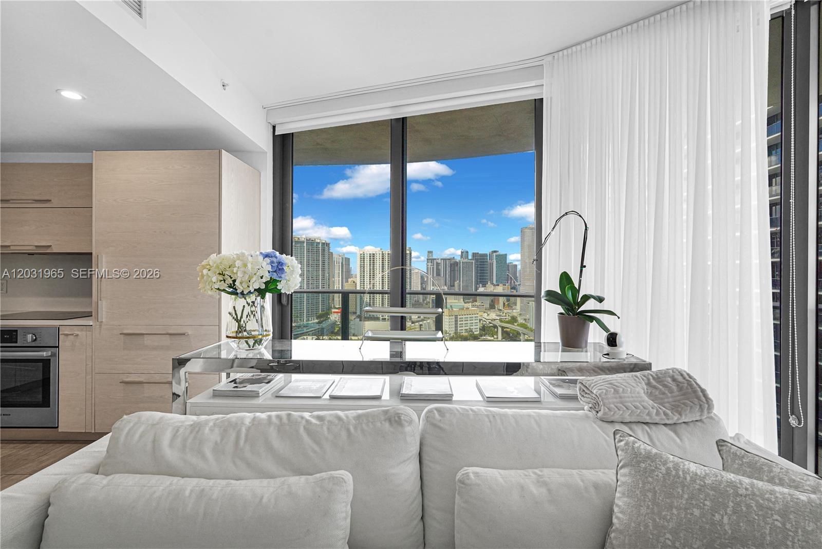 A modern living room features a white sofa, a glass console table, and floor-to-ceiling windows — 45 SW 9th St # 2901, Miami FL 33130, MIAMI, FL