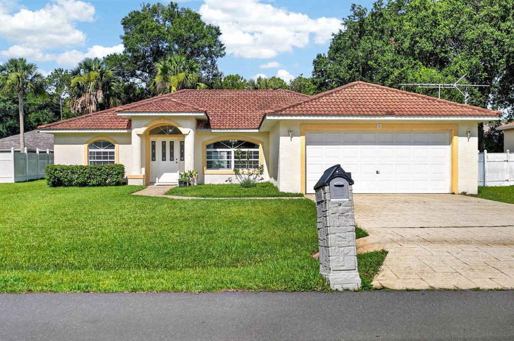A single-story house with a tiled roof, white garage door, and a stone mailbox — 8 PILLORY LANE, PALM COAST, FL