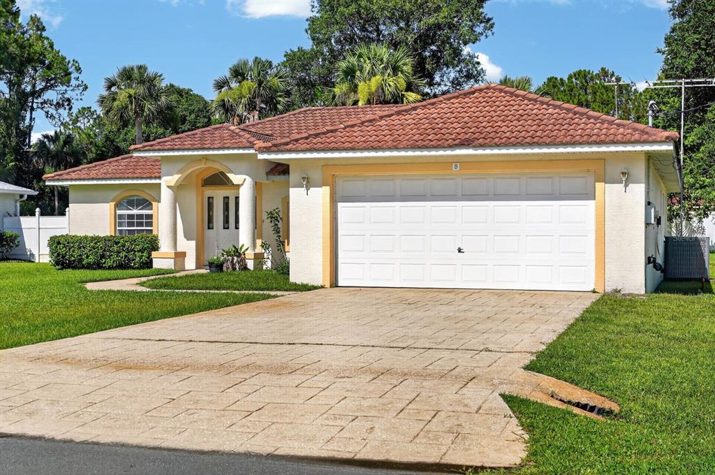 A single-story house with a tiled roof, white garage door, and a paved driveway — 8 PILLORY LANE, PALM COAST, FL