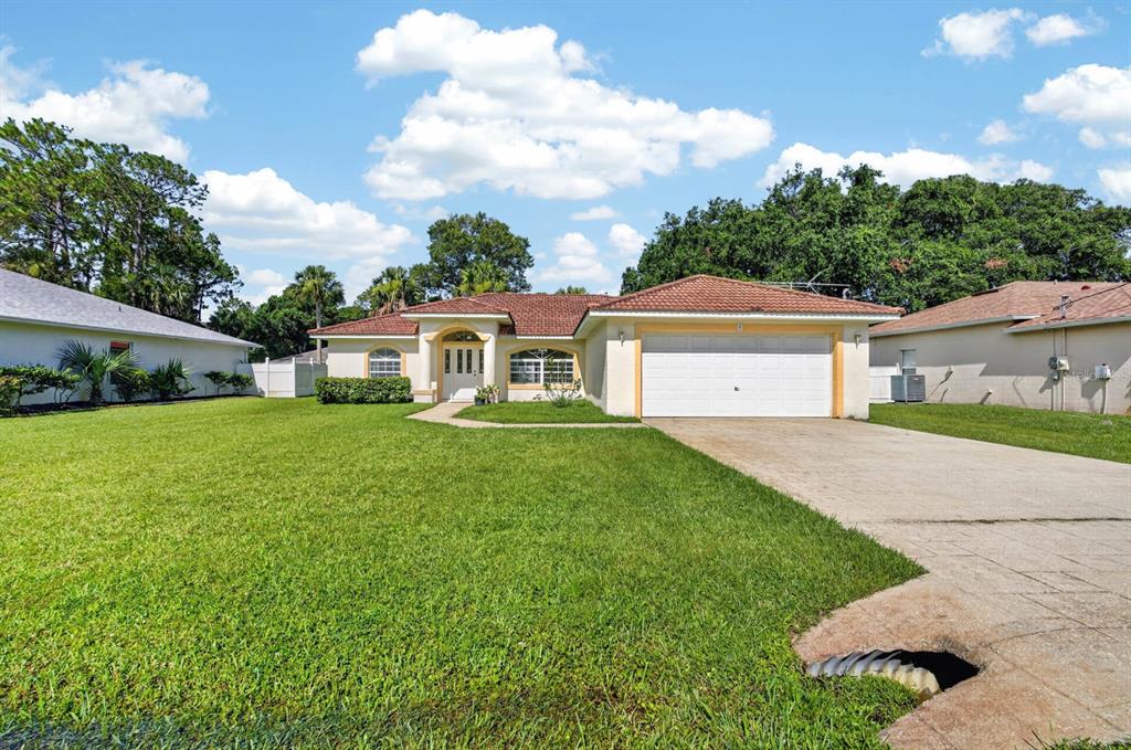 A single-story house with a white garage, a tiled roof, and a large front lawn — 8 PILLORY LANE, PALM COAST, FL