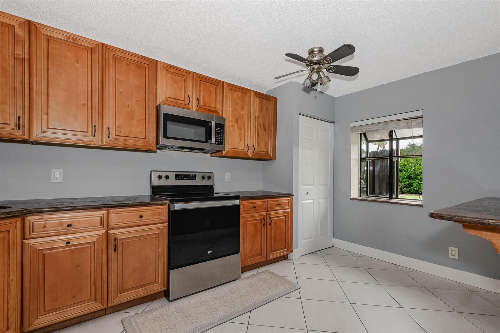 A kitchen features wood cabinets, stainless steel appliances, gray walls, and a tile floor — 161 Meadows Drive # 161, Boynton Beach FL 33436, BOYNTON BEACH, FL