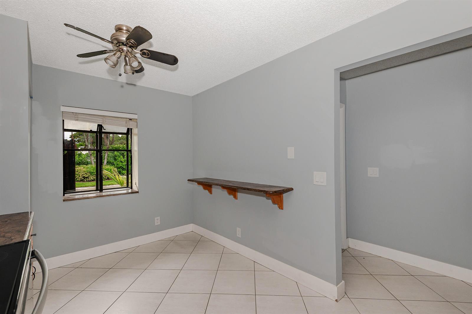 A room with light blue walls, white tile floors, a ceiling fan, and a wooden shelf — 161 Meadows Drive # 161, Boynton Beach FL 33436, BOYNTON BEACH, FL