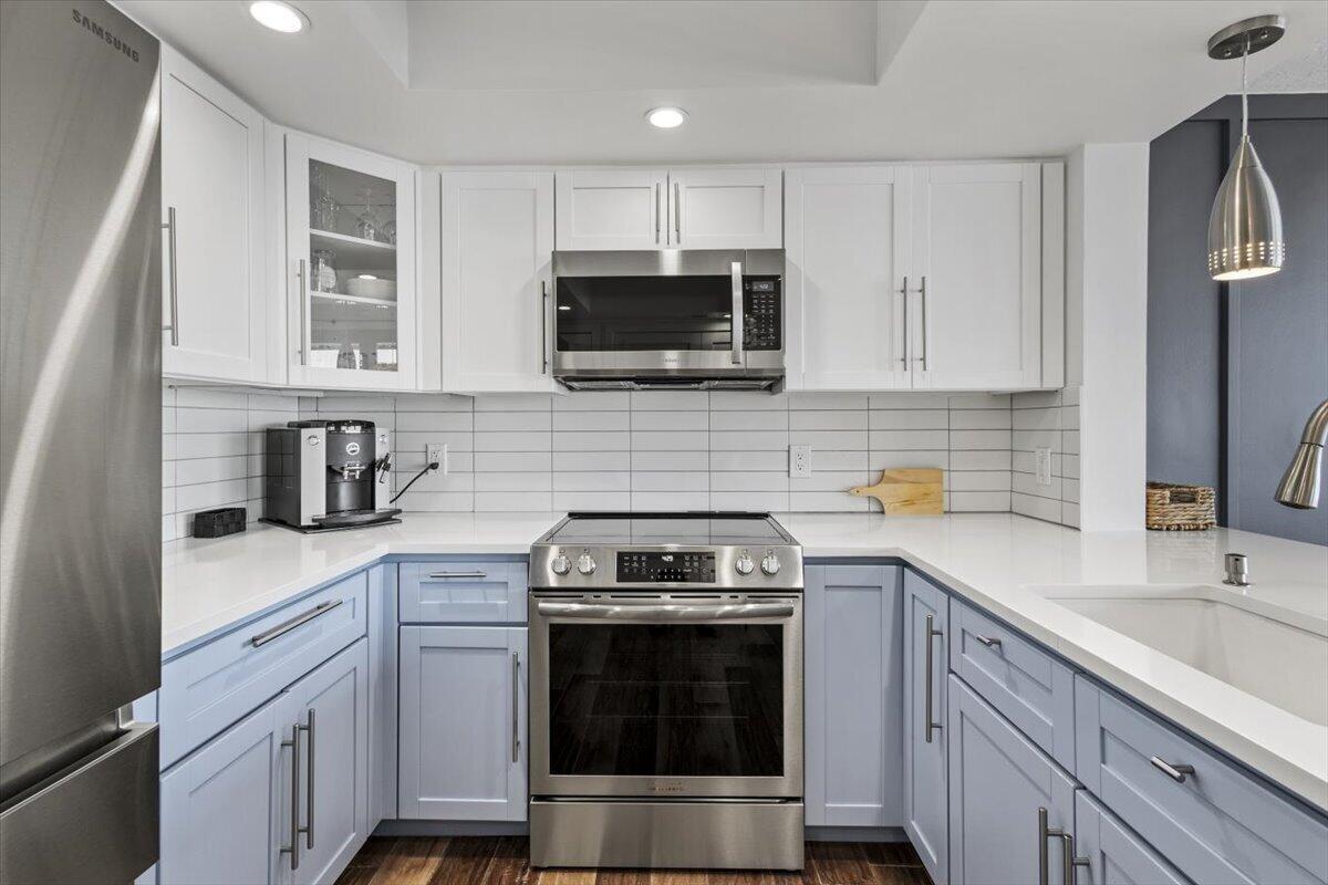 A kitchen features white upper cabinets, light blue lower cabinets, stainless steel appliances, and white countertops — 8750 S Ocean Drive # 334, Jensen Beach FL 34957, JENSEN BEACH, FL