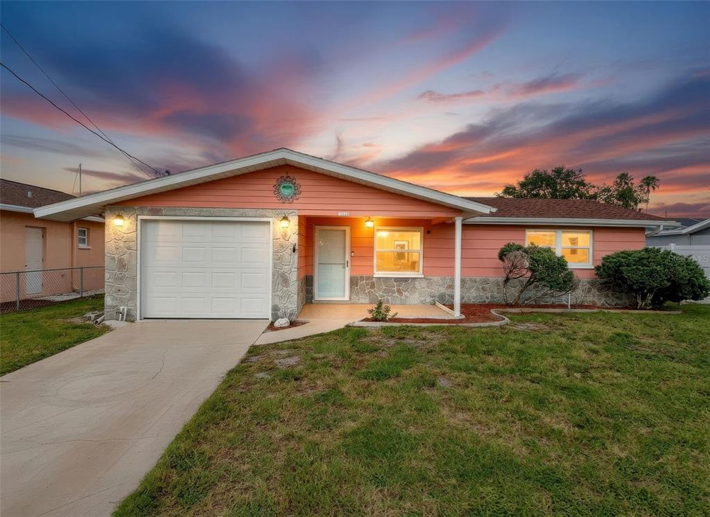 A single-story house with pink siding, a stone facade, and a one-car garage — 13530 MARIA DRIVE, HUDSON, FL