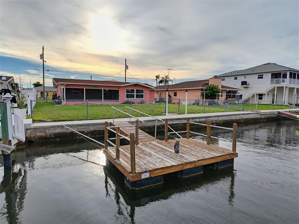 A floating wooden dock sits in a canal in front of two residential houses — 13530 MARIA DRIVE, HUDSON, FL