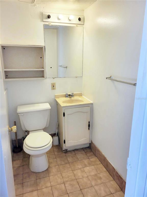 A small bathroom features a white toilet, a vanity with a sink, and wall shelving — 914 SW 8TH AVENUE UNIT 26, GAINESVILLE, FL