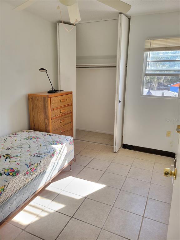 A bedroom features a twin bed, a wooden dresser, a closet, and tiled flooring — 914 SW 8TH AVENUE UNIT 26, GAINESVILLE, FL