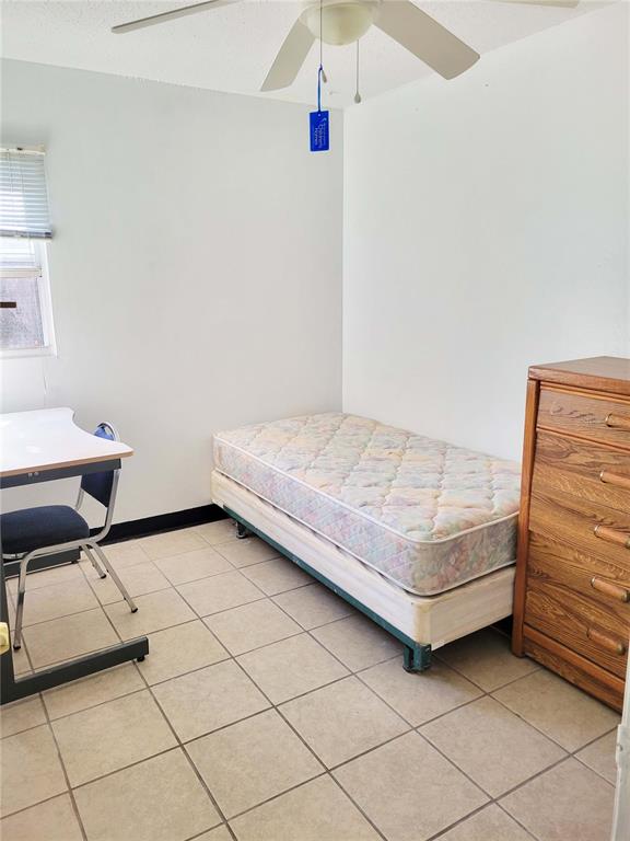 A bedroom features a twin bed, a wooden dresser, a desk with a chair, and tile flooring — 914 SW 8TH AVENUE UNIT 26, GAINESVILLE, FL