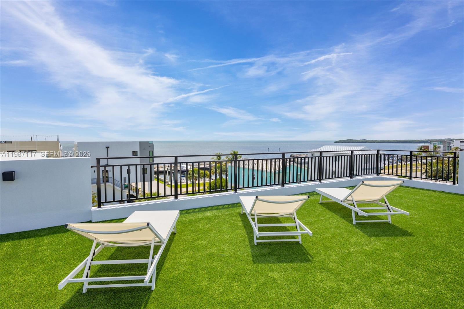 A rooftop terrace features artificial turf, three lounge chairs, and a metal railing overlooking water — 94825 Overseas Hwy 209, Key Largo FL 33037, KEY LARGO, FL