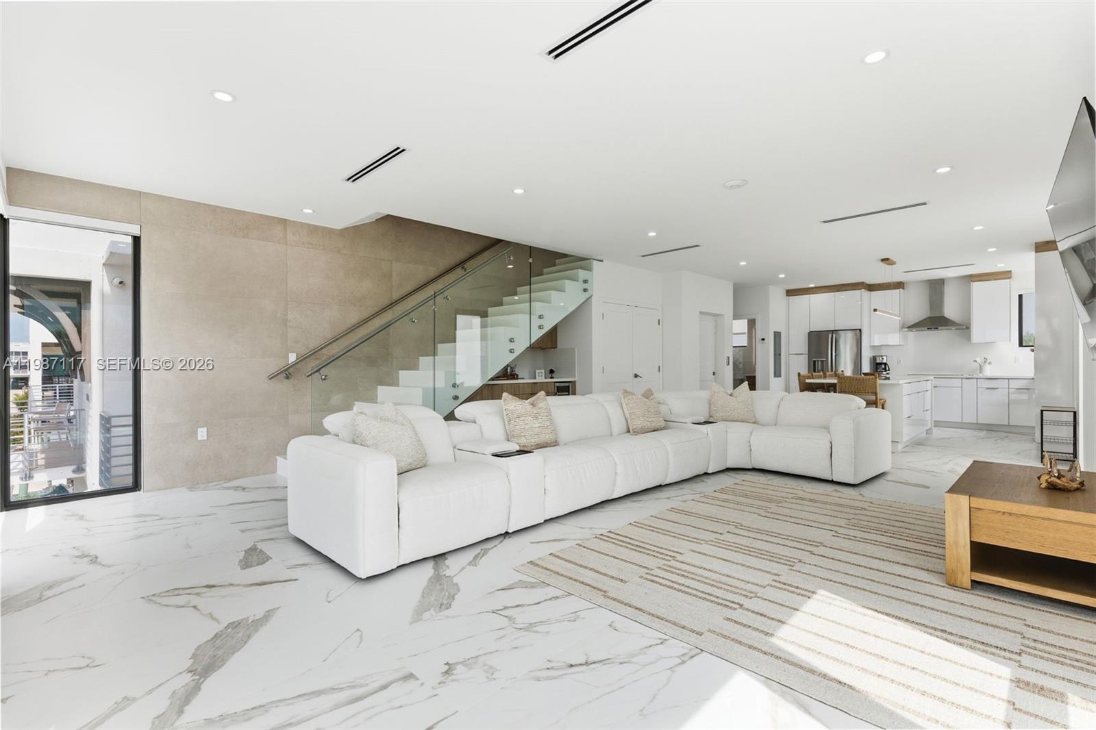 A modern open-concept living room features a white sectional sofa, marble floors, and glass-railed stairs — 94825 Overseas Hwy 209, Key Largo FL 33037, KEY LARGO, FL