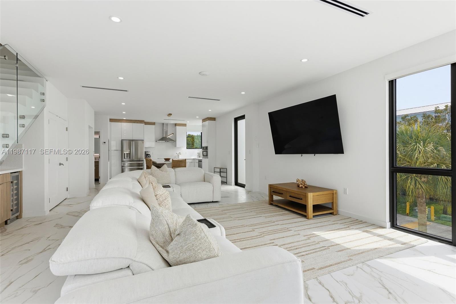 A modern living room features a large white sectional sofa, marble floors, and a wall-mounted television — 94825 Overseas Hwy 209, Key Largo FL 33037, KEY LARGO, FL