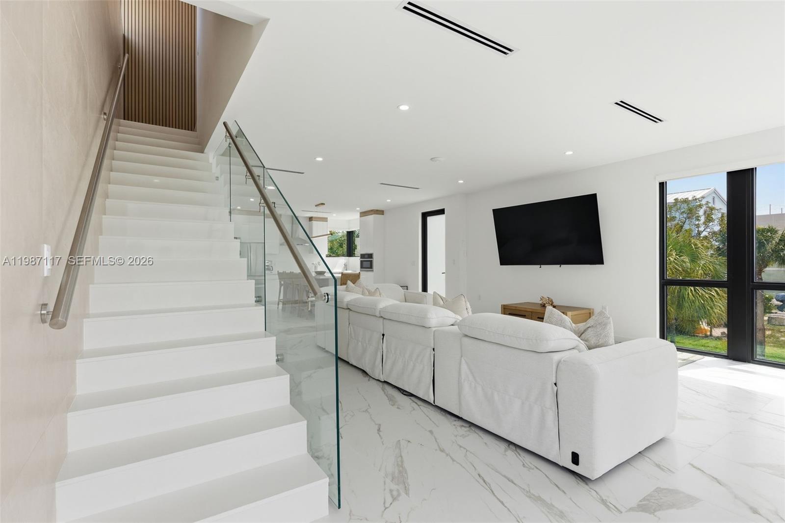 A modern living room features white marble floors, a glass-railed staircase, and a white sofa — 94825 Overseas Hwy 209, Key Largo FL 33037, KEY LARGO, FL