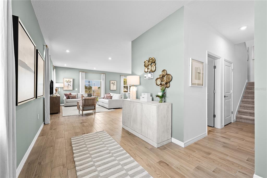 An open-concept living area features light-colored walls, wood-look tile flooring, and a staircase — 806 CASTLEFORD AVENUE NE, PALM BAY, FL
