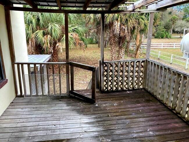A wooden deck with a screened-in area, lattice railings, and a view of palm trees — 16500 S US HIGHWAY 19, SALEM, FL