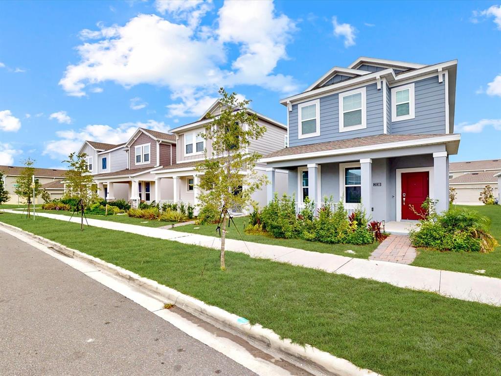 A row of suburban two-story houses with blue and tan siding and front porches — 2538 PEACE OF MIND AVENUE, KISSIMMEE, FL