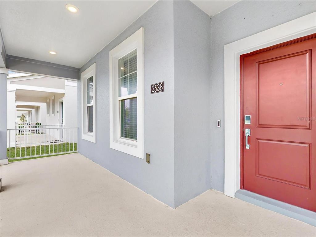 A covered porch features a red front door, a window, and a house number — 2538 PEACE OF MIND AVENUE, KISSIMMEE, FL