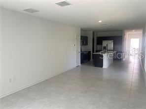 An open-concept living area features light tile flooring, white walls, and a modern kitchen — 1738 FOREMAN ROAD, EAGLE LAKE, FL