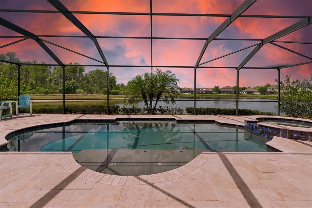 A screened-in swimming pool and spa overlooking a lake at sunset — 13218 BATTEN LANE, ODESSA, FL