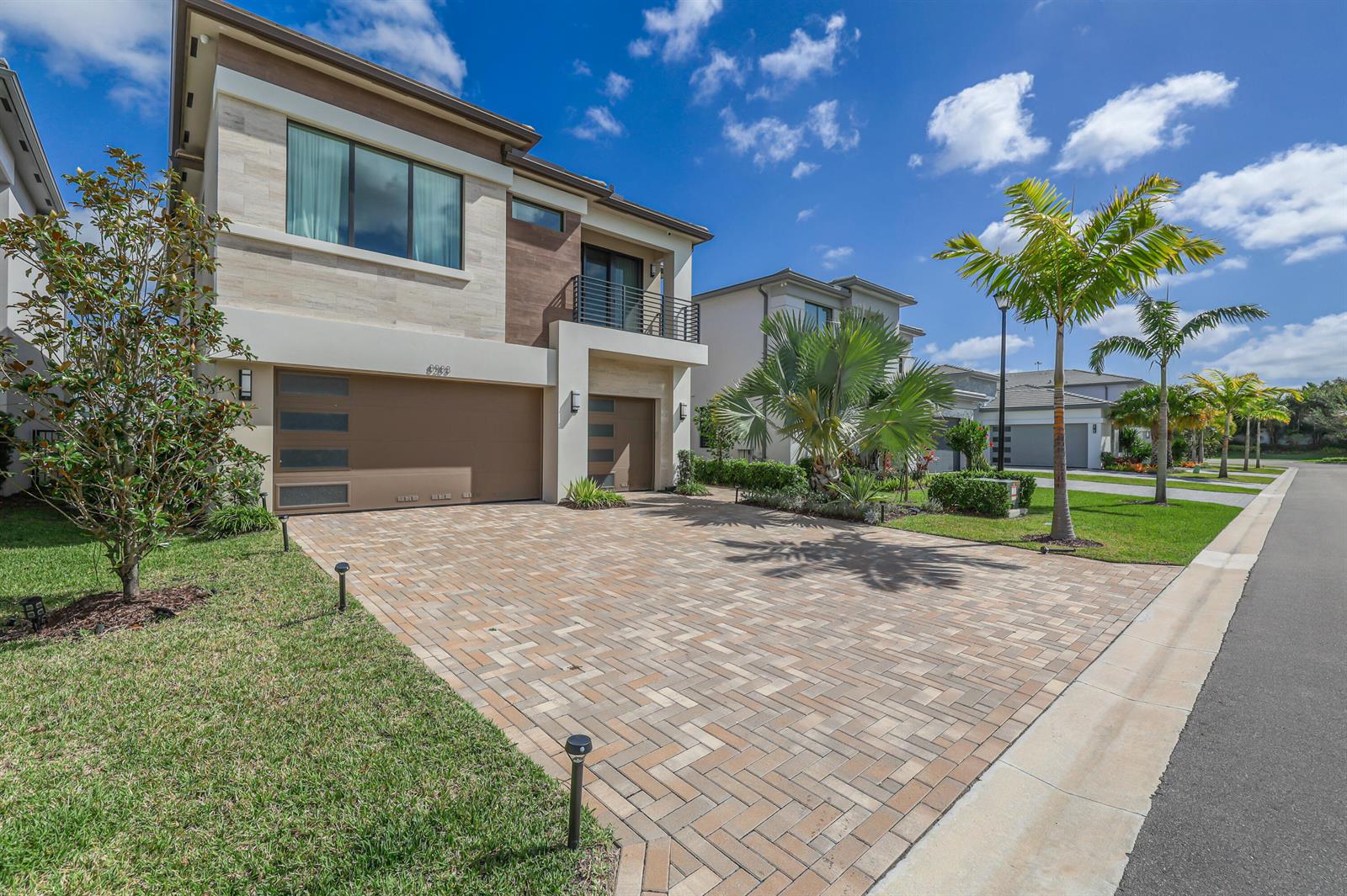 A two-story house with a paved driveway, garage, and palm trees under a blue sky — 8283 Royal County Down Road, Boca Raton FL 33434, BOCA RATON, FL