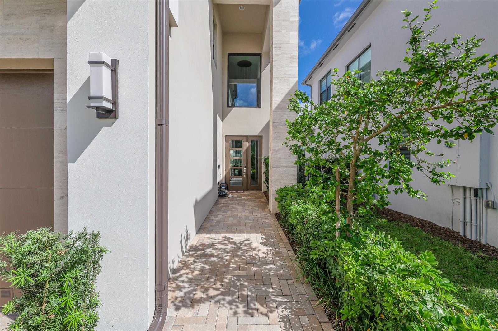 A paved walkway leads to a modern front entrance with double glass doors and stone accents — 8283 Royal County Down Road, Boca Raton FL 33434, BOCA RATON, FL