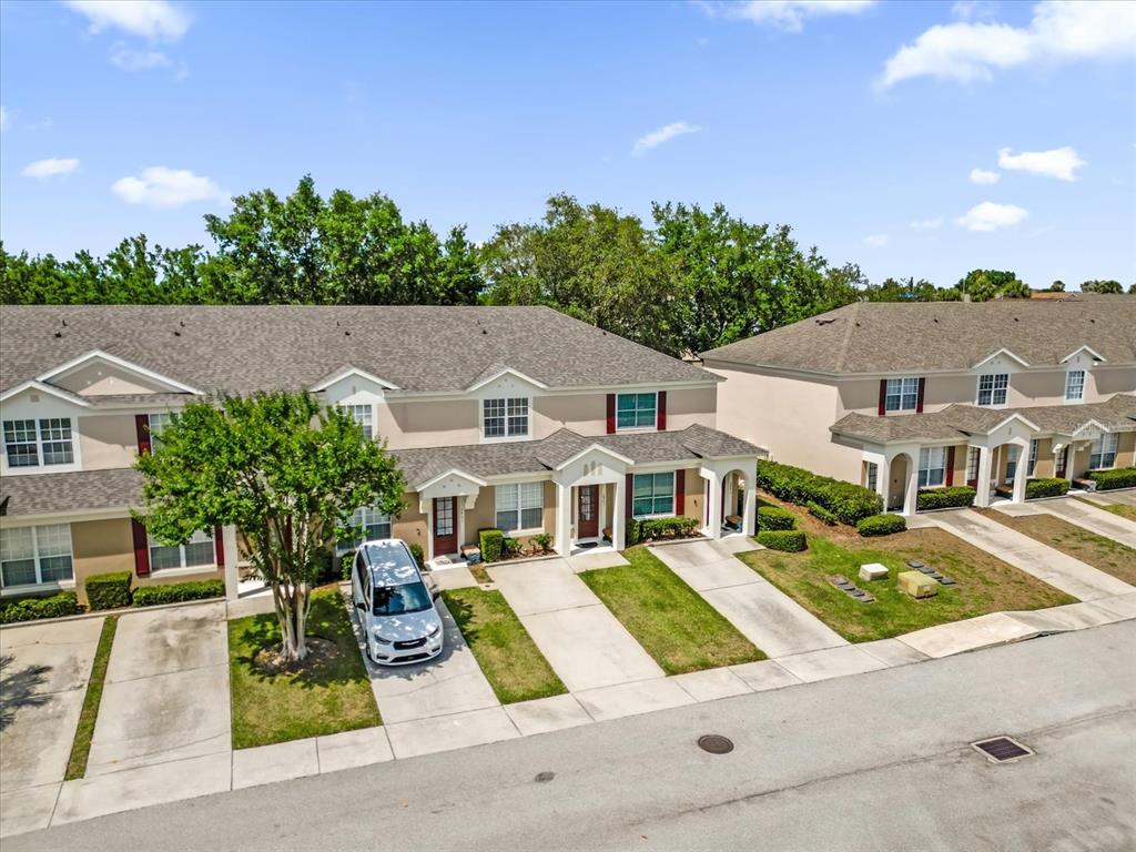 An aerial view of a row of two-story townhomes with driveways and green lawns — 2403 SILVER PALM DRIVE, KISSIMMEE, FL