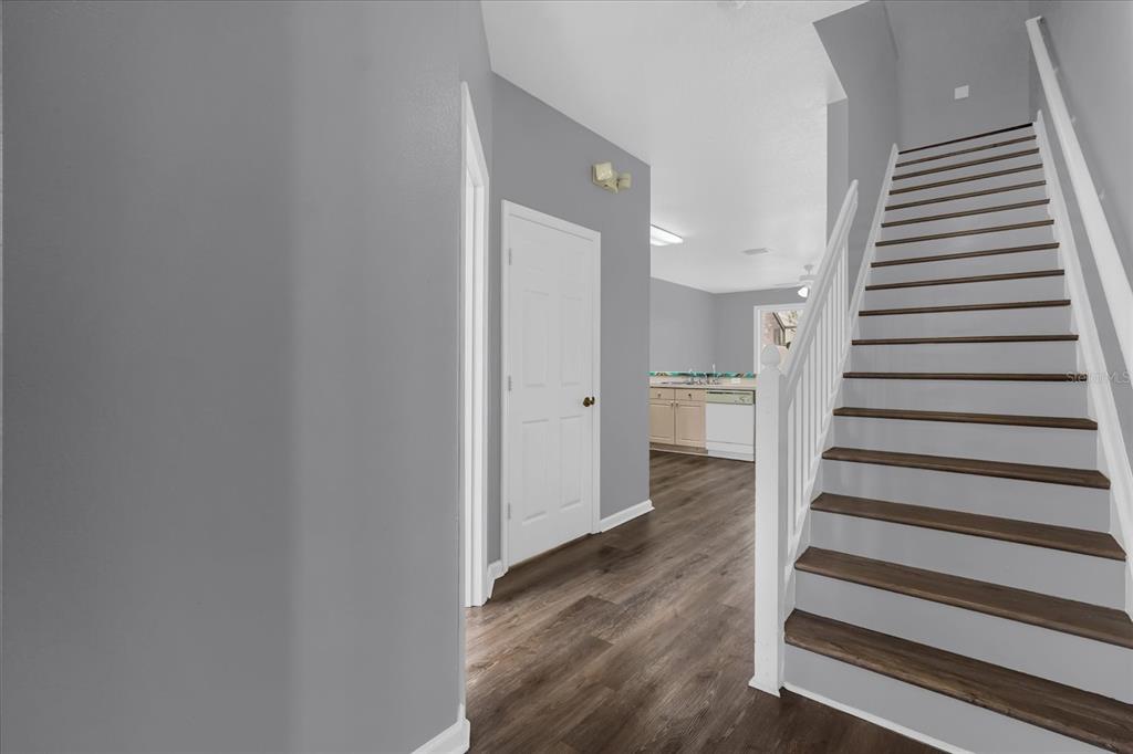 A staircase with dark wood treads and white risers leads upward next to a hallway — 2403 SILVER PALM DRIVE, KISSIMMEE, FL