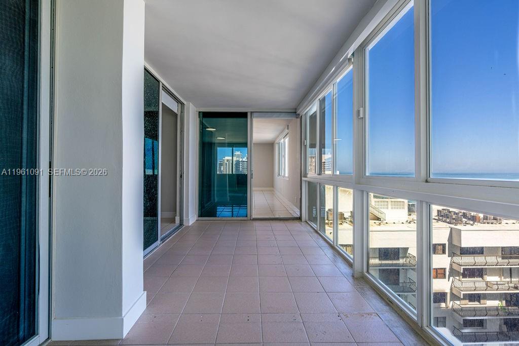 A sunroom with tiled flooring, floor-to-ceiling windows, and views of the ocean and buildings — 5401 Collins Ave # 919, Miami Beach FL 33140, MIAMI BEACH, FL