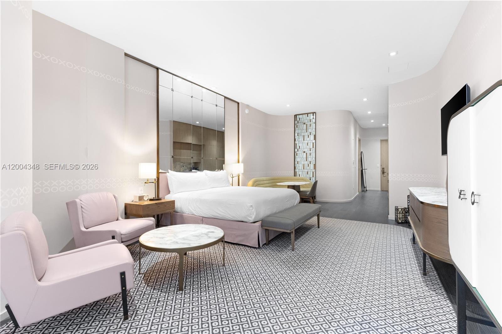A modern hotel bedroom features a king bed, pink armchairs, and a patterned carpet — 801 Miami Ave # 709, Miami FL 33130, MIAMI, FL