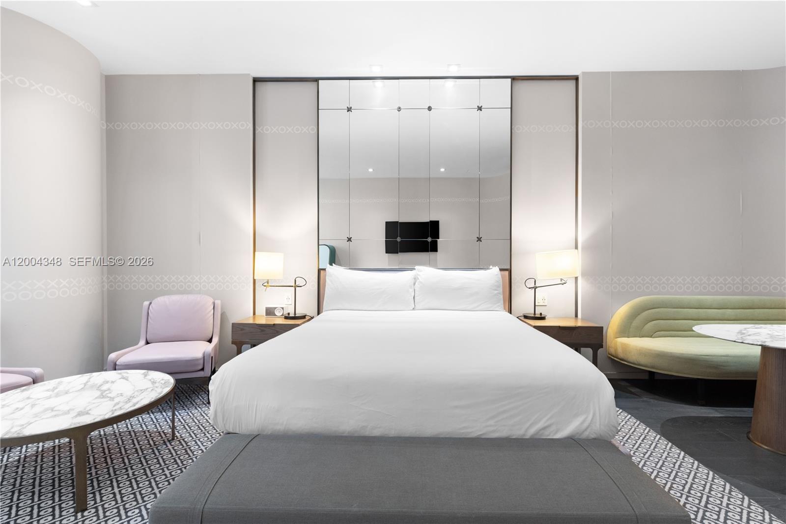 A bedroom features a central bed, mirrored wall paneling, two side tables, and patterned carpeting — 801 Miami Ave # 709, Miami FL 33130, MIAMI, FL